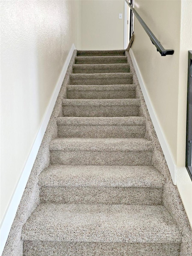 staircase featuring carpet and baseboards