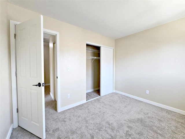 unfurnished bedroom with a closet, baseboards, and carpet flooring