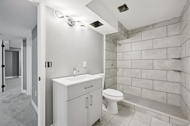 bathroom with tile patterned floors, vanity, toilet, and a tile shower