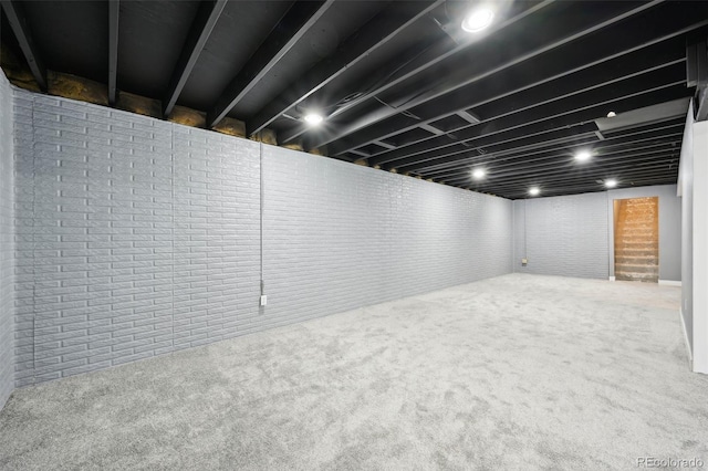 basement featuring carpet and brick wall