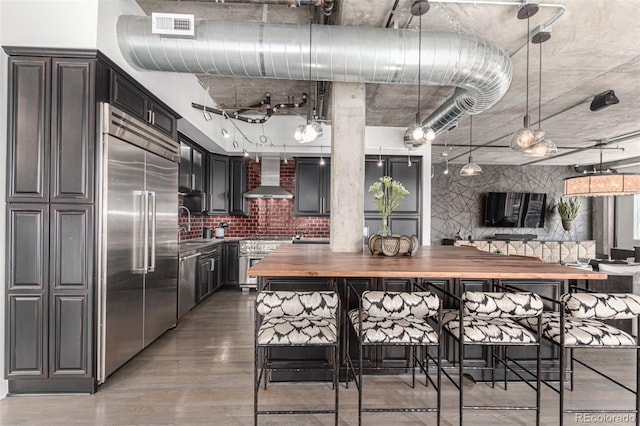 1735 19th St Unit 6D, Denver, CO 80202 - kitchen featuring wooden counters, wall chimney exhaust hood, high quality appliances, a sink, and light wood-type flooring