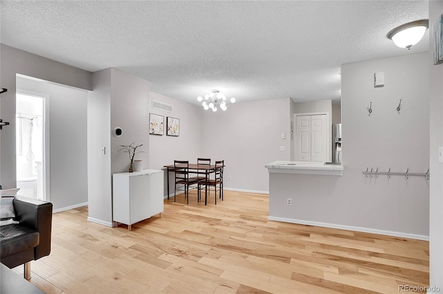 dining space featuring baseboards, visible vents, light wood-style flooring, and a textured ceiling