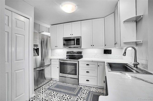 kitchen featuring white cabinets, stainless steel appliances, a sink, and light tile patterned flooring