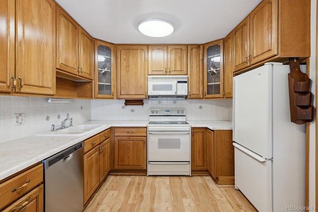 kitchen featuring white appliances, light hardwood / wood-style flooring, sink, and decorative backsplash