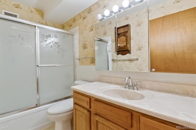 full bathroom with shower / bath combination with glass door, vanity, backsplash, tile walls, and toilet