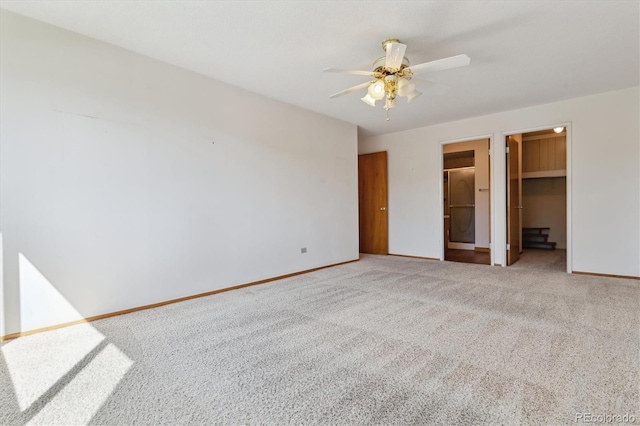 unfurnished bedroom featuring a spacious closet, a closet, ensuite bathroom, carpet flooring, and ceiling fan