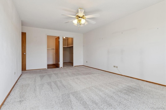 unfurnished bedroom featuring a walk in closet, ceiling fan, and light carpet