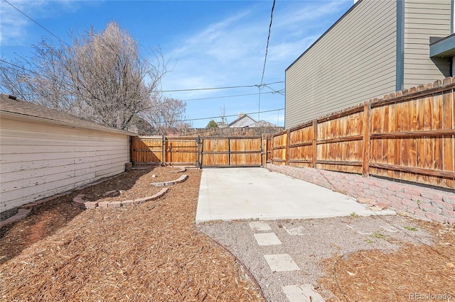 view of yard with a patio, a fenced backyard, and a gate