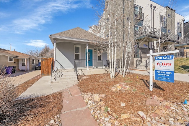 view of front of home with stucco siding, roof with shingles, and a porch