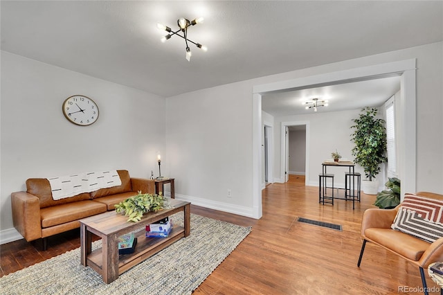 living room featuring visible vents, baseboards, and wood finished floors