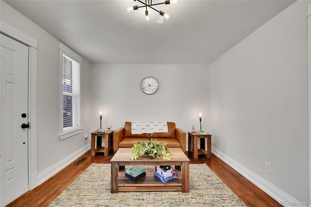 living area with visible vents, baseboards, dark wood-style flooring, and a chandelier