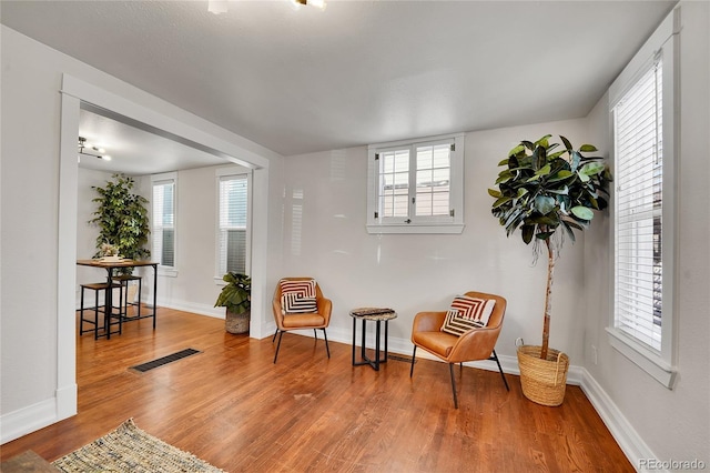 sitting room featuring wood finished floors, visible vents, and baseboards