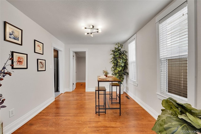 dining area with light wood finished floors, visible vents, and baseboards