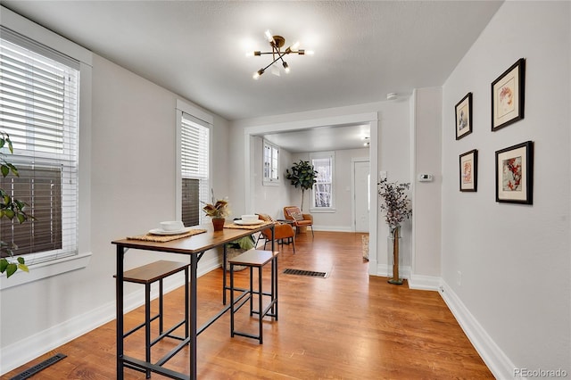 dining area featuring a notable chandelier, baseboards, visible vents, and light wood finished floors