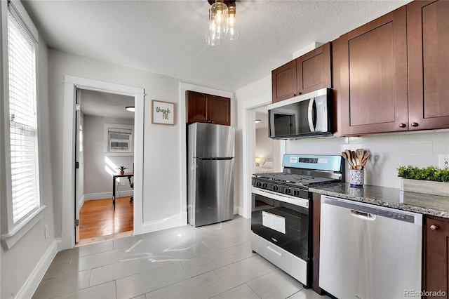 kitchen featuring dark stone counters, light tile patterned flooring, appliances with stainless steel finishes, and a textured ceiling