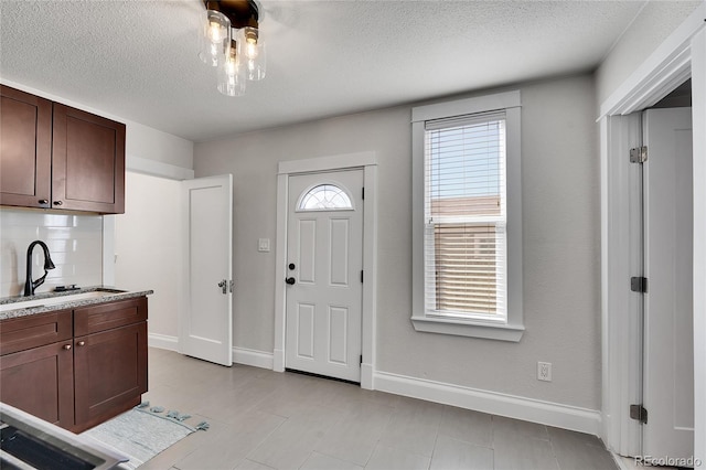 interior space featuring tasteful backsplash, dark brown cabinetry, baseboards, and a sink