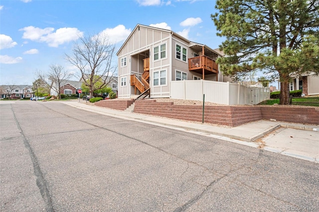 view of front of home featuring fence, board and batten siding, a residential view, and a balcony