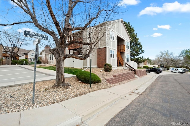 view of property exterior featuring a residential view, board and batten siding, stairs, and brick siding