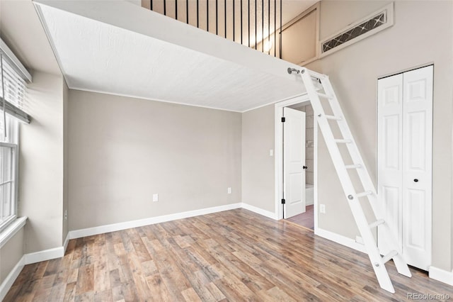 unfurnished living room featuring wood finished floors, baseboards, and stairway
