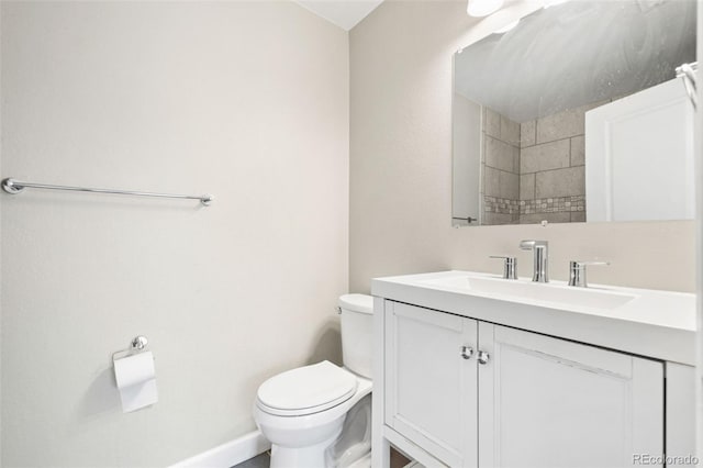 bathroom featuring toilet, vanity, and baseboards