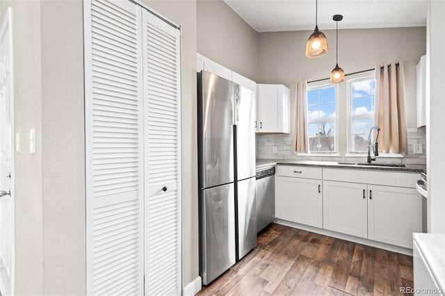 kitchen with stainless steel appliances, a sink, decorative backsplash, white cabinets, and dark wood-style floors