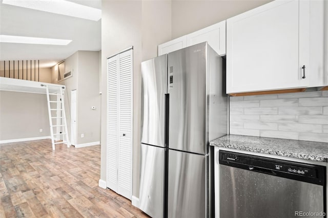 kitchen with stainless steel appliances, decorative backsplash, white cabinets, and light wood-style flooring