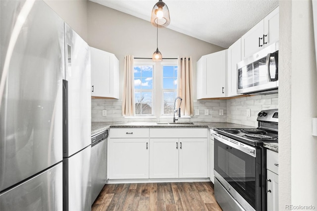 kitchen with appliances with stainless steel finishes, lofted ceiling, a sink, backsplash, and white cabinets
