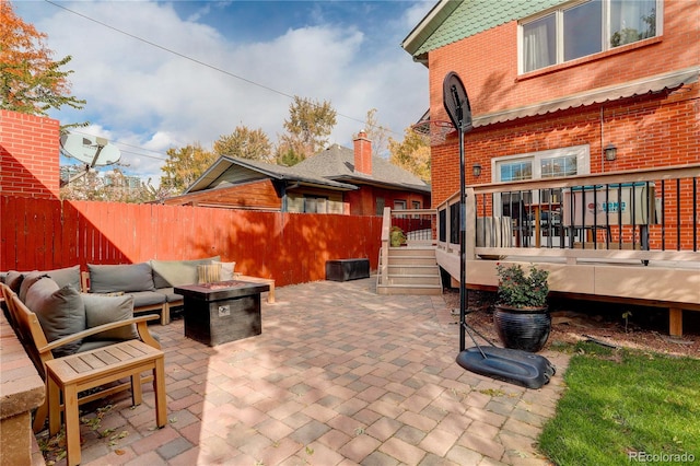 view of patio / terrace featuring a wooden deck, fence, and an outdoor living space with a fire pit