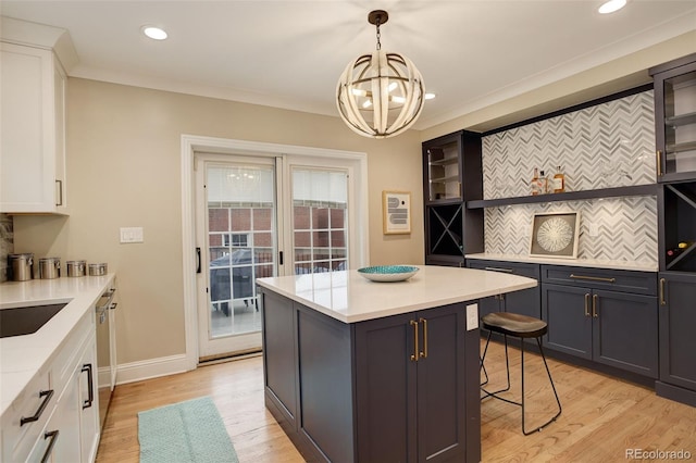 kitchen featuring open shelves, ornamental molding, a breakfast bar, and white cabinetry