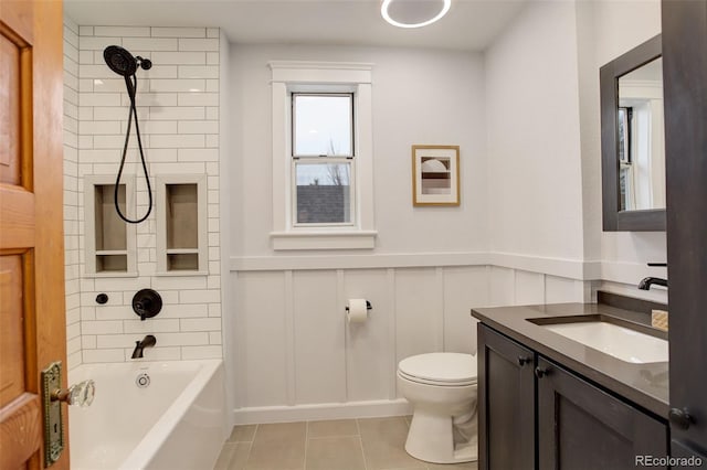 bathroom with a wainscoted wall, toilet, tub / shower combination, vanity, and tile patterned floors