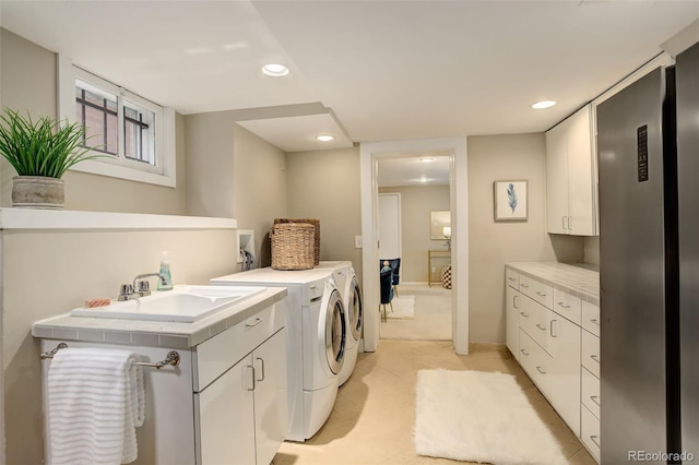 clothes washing area with a sink, washing machine and clothes dryer, cabinet space, and recessed lighting