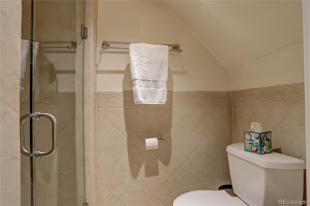 bathroom featuring lofted ceiling, a stall shower, toilet, and tile walls