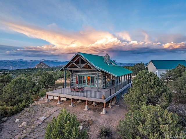 back house at dusk with a deck with mountain view