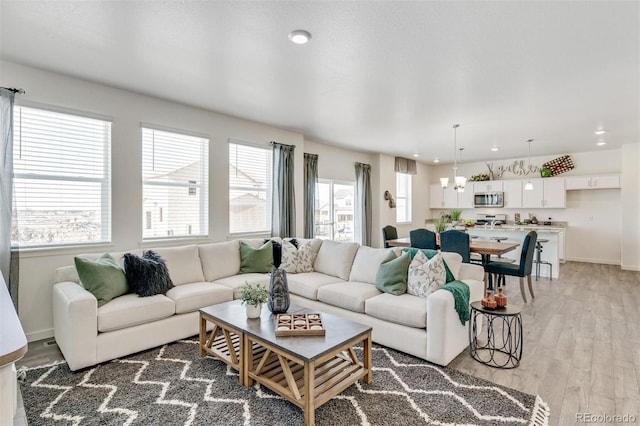 living room with a chandelier, a wealth of natural light, and light hardwood / wood-style floors