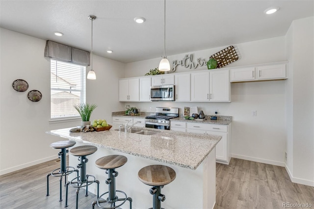 kitchen featuring decorative light fixtures, sink, white cabinetry, and stainless steel appliances