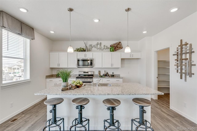 kitchen featuring a kitchen bar, plenty of natural light, white cabinets, and appliances with stainless steel finishes