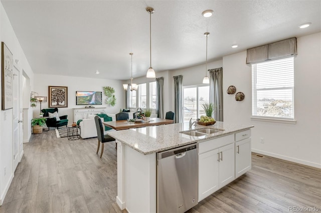 kitchen with white cabinetry, plenty of natural light, stainless steel dishwasher, and a center island with sink