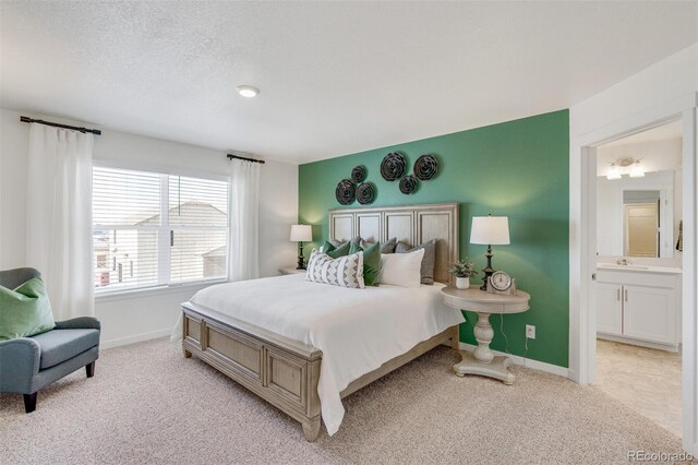 carpeted bedroom with ensuite bathroom, sink, and a textured ceiling