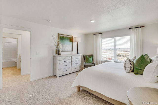 carpeted bedroom featuring a textured ceiling and ensuite bathroom