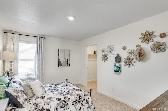 bedroom featuring a textured ceiling, a spacious closet, light carpet, and a closet