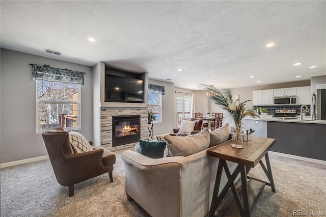 living area featuring light colored carpet, a textured ceiling, and a fireplace