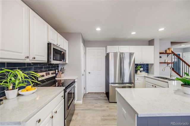 kitchen with a sink, light wood-type flooring, recessed lighting, decorative backsplash, and appliances with stainless steel finishes