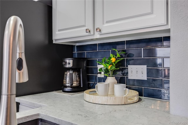 interior details with white cabinetry, light stone counters, and tasteful backsplash