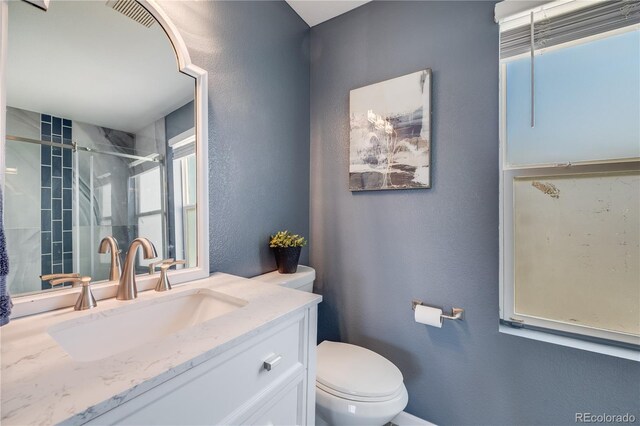 bathroom featuring a textured wall, an enclosed shower, toilet, and vanity