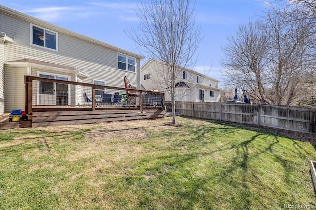 rear view of house with a lawn, fence, and a deck
