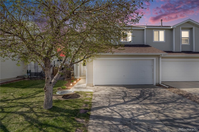 view of front of home with a yard, an attached garage, driveway, and a shingled roof