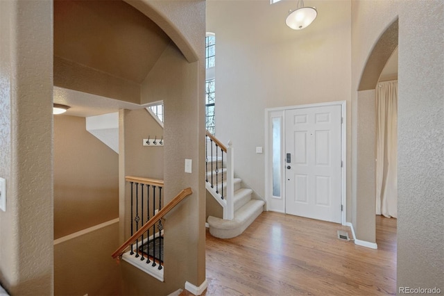entryway with baseboards, stairway, visible vents, arched walkways, and wood finished floors