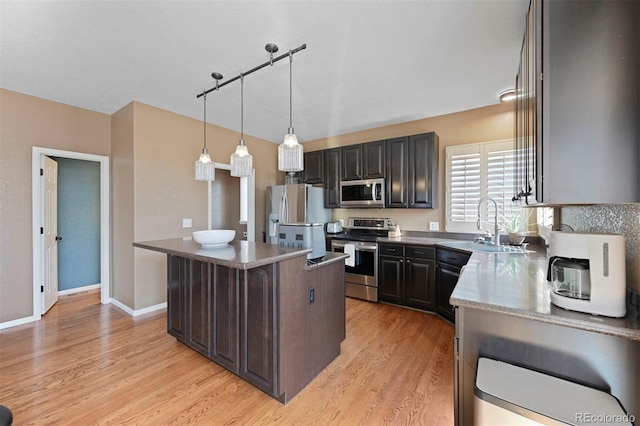 kitchen featuring a kitchen island, light wood finished floors, a sink, and appliances with stainless steel finishes