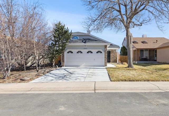 view of front of house with brick siding, a front lawn, fence, a garage, and driveway