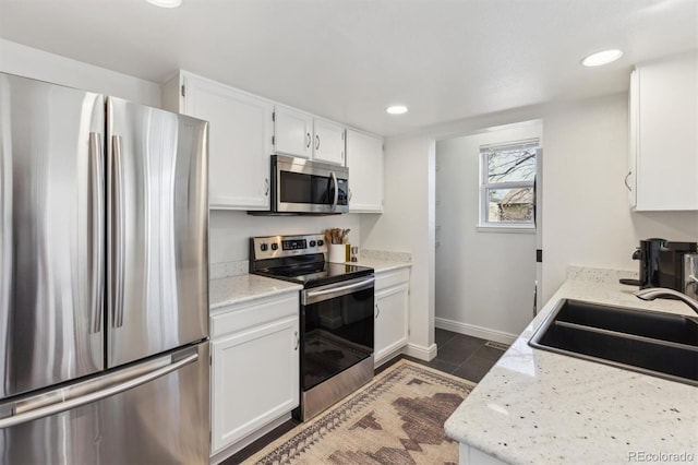 kitchen with baseboards, recessed lighting, stainless steel appliances, white cabinetry, and a sink